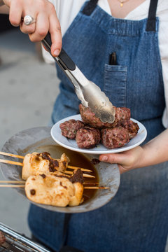 Chef holding grilled lamb kofta and mushroom kebabs