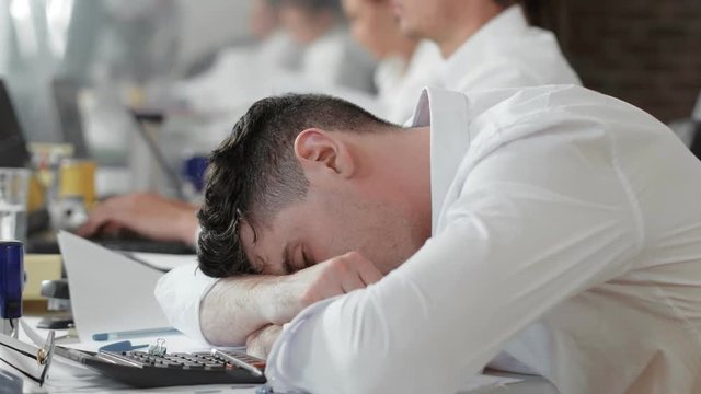 Overworked employee tired and sleeping at work.