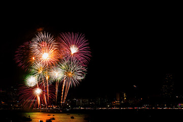 Many flashing fireworks with night cityscape background celebrate New Year.