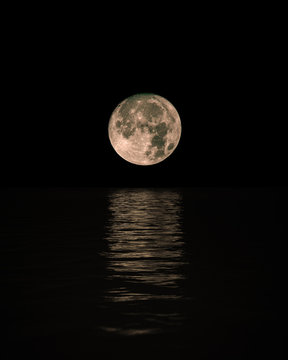 Full Moon Rising Over Calm Sea with reflection on water, Vertical © Lambros Kazan