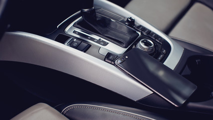 Fototapeta na wymiar smartphone in red case with dual camera in the interior of a modern luxury car