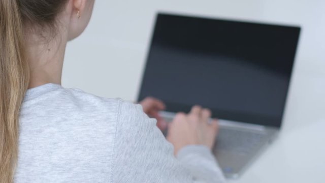 Young Woman Working On Laptop in Office, Back View