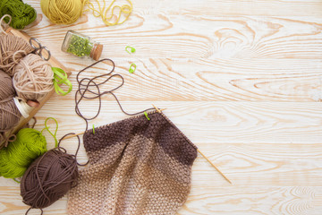 A woman knits a white and broun knitted fabric of woolen yarn. Knitting needles. Aged background....