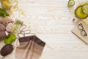 A woman knits a white and broun knitted fabric of woolen yarn. Knitting needles. Aged background....