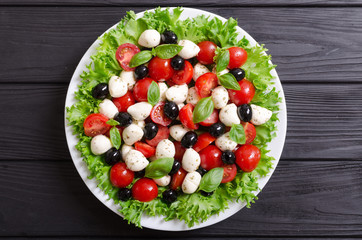 Salad with basil , tomatoes , olives and mozzarella