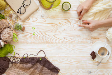 A woman knits a white and broun knitted fabric of woolen yarn. Knitting needles. Aged background....