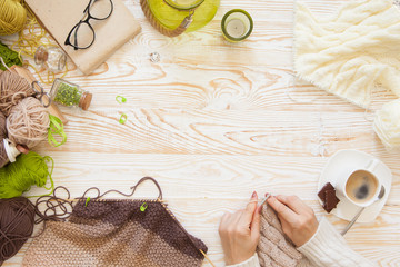 A woman knits a white and broun knitted fabric of woolen yarn. Knitting needles. Aged background....