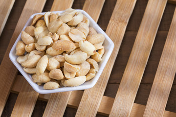 Salted peanut seeds on wooden background - Arachis hypogaea
