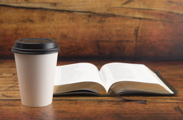 Bible and a Cup of Coffee in a Disposable Paper Cup on a Wooden Table