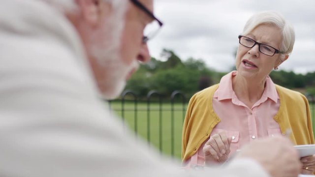 Senior Affluent Couple Talking Over A Cafe Breakfast Table Outdoors