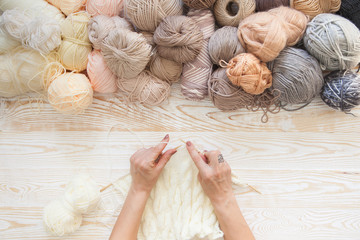 Wool and cotton yarn for knitting of neutral natural color. The woman knits knitting.