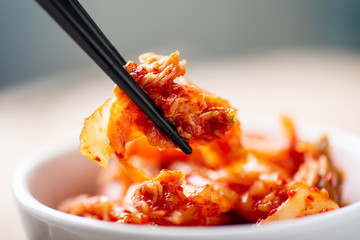 Hand holding chopsticks for eating kimchi cabbage, Korean food - obrazy, fototapety, plakaty