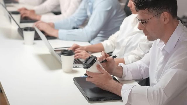 Close-up on office worker drawing smile on cup of coffee.