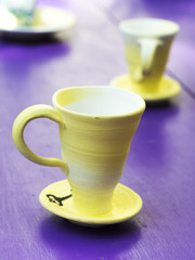 Close-up of handcrafted tea cups on a purple color table. Very distinctive color between cups and table.