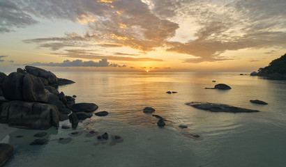 Fototapeta na wymiar Colourful sunrise over sea lagoon and rocks on a tropical island 