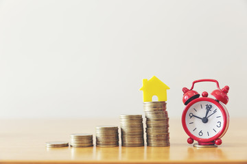 Model of house with coins on wooden table