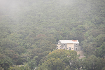 A traditional home on the hillside with fog around in HongKong