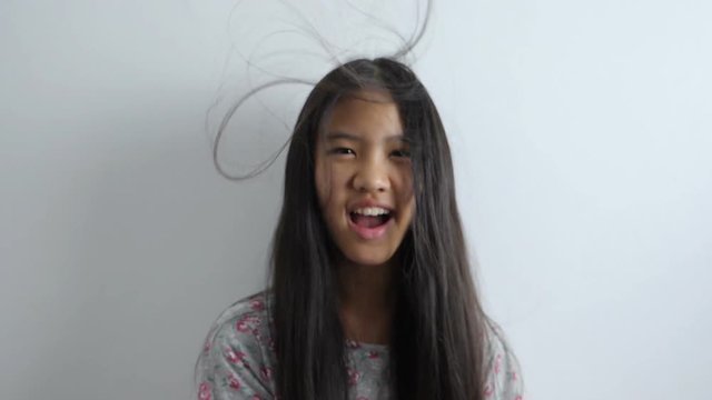 4K Slow motion shot of Happy Asian girl playing with hair blowing on white background
