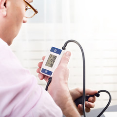 Man read measurement results from personal digital blood pressure monitor