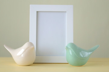 Interior frame mockup. empty frame with beige ceramic birds on a  yellow wooden background.design frame mockup with copy space.