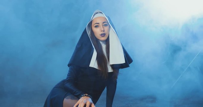 Bad nun is sitting on the floor and looking sexually at the camera