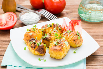 Baked young potatoes in spices and oil with arugula on a plate on a wooden table