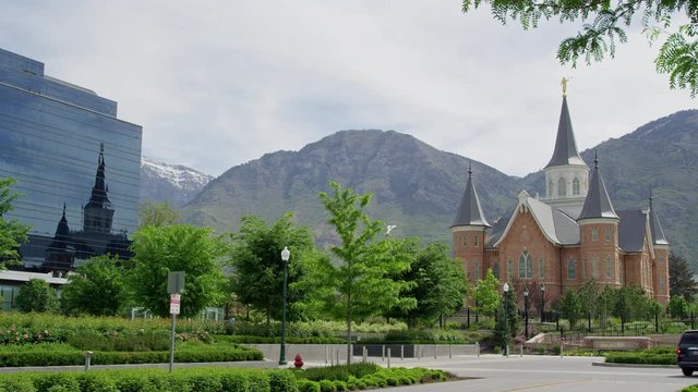 Wide view of Provo City Center Temple reflecting in Nu Skin building with the Wasatch Mountains behind.