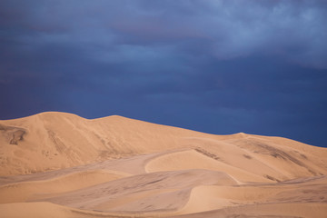 Tall Sand Dunes Under Stormy Skies