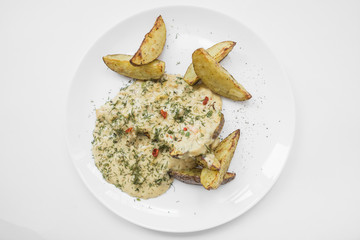 куриное рагу в сметанном соусе с картофельными дольками на белой тарелке.