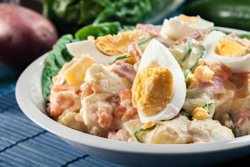 Delicious potato salad with ham, egg and cucumber