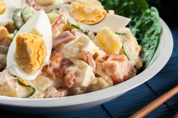 Delicious potato salad with ham, egg and cucumber