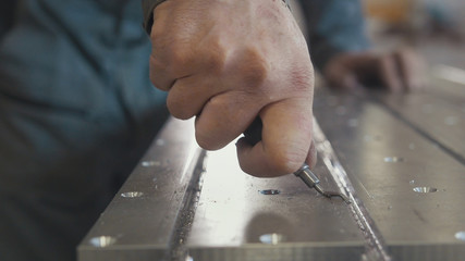 Male hands makes chamfering removing burrs on metal panel with a scraper