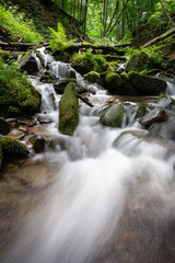 Beautiful mountain rainforest waterfall with fast flowing water and rocks, long exposure.