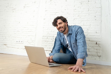 freelance hipster working from home on a laptop with white brick wall background.