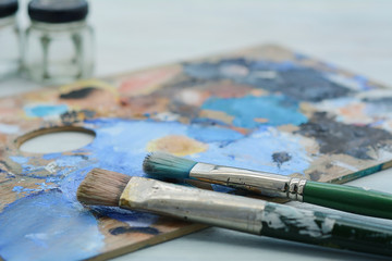 Fototapeta premium Artist's palette with colorful oil paint strokes and paintbrushe