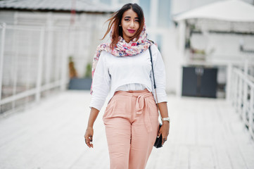 Fototapeta premium Fashion arabian girl at white blouse and peach pants posed outdoor. Stylish muslim woman.