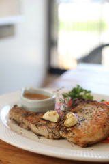 grilled pork chop with vegetable on dish with wood table background