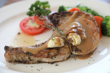 grilled pork chop with vegetable on dish with wood table background
