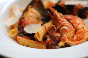 Penne pasta tomato sauce arabiata with seafood on wood background vintage style