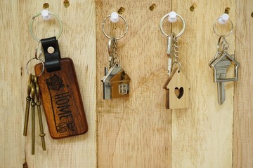 House key with wooden home keyring hanging on wood board background, property concept, copy space - 210954064