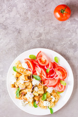 Fried zucchini with feta cheese, tomatoes, herbs and onions on a plate on a table. Top view. Copy space