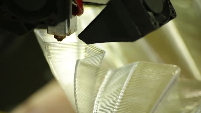Closeup: A 3d Printer Nozzle lays down the next layer of its construction