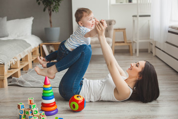 Young pretty mother playing with her little son. Cheerful family having fun indoors with little...