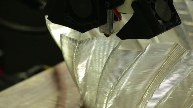 A 3d printing head/nozzle lays down the next layer of the object it is building