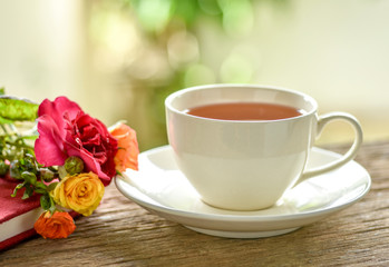 Hot tea cup and roses from the garden. Relax tea time in the garden with selective focus and shallow depth of field.