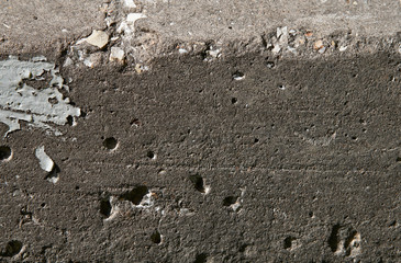 Old flaky white paint peeling off a grungy cracked wall. Cracks, scrapes, peeling old paint and plaster on background of old cement wall. An old cement stone wall as vintage cracked.
