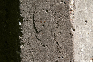 Old flaky white paint peeling off a grungy cracked wall. Cracks, scrapes, peeling old paint and plaster on background of old cement wall. An old cement stone wall as vintage cracked.