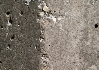 Old flaky white paint peeling off a grungy cracked wall. Cracks, scrapes, peeling old paint and plaster on background of old cement wall. An old cement stone wall as vintage cracked.