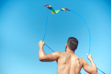back view of man with colorful kite against clear blue sky