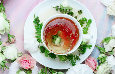 White cup of spring tea with rose petals